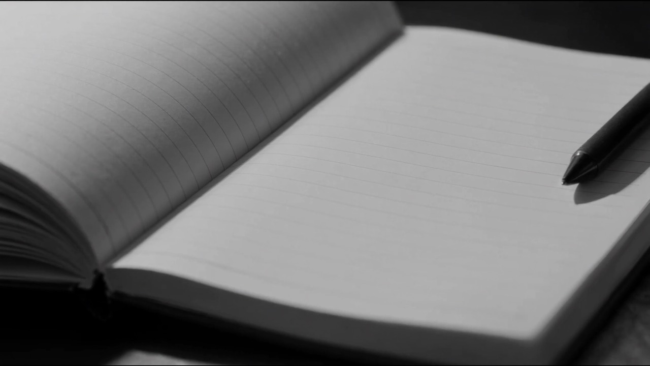 Nyitott, üres notesz tollal, készen az írásra, közeli makró