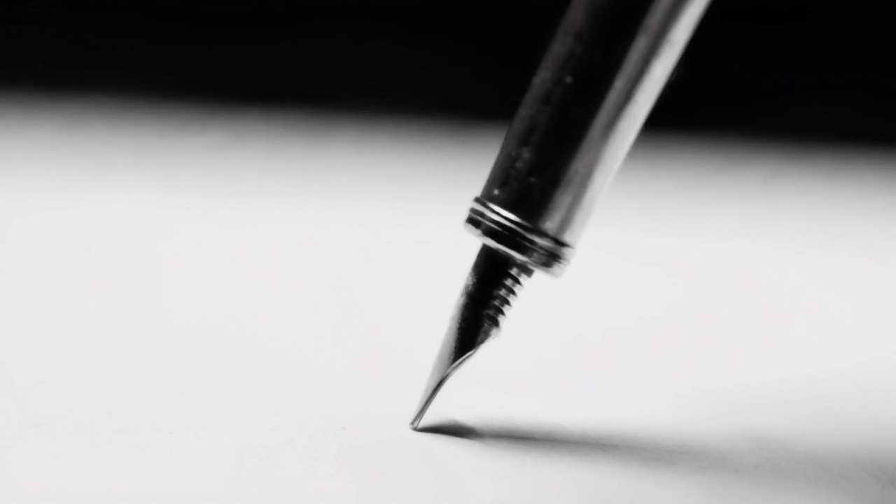 A fountain pen writing on blank paper, macro close-up