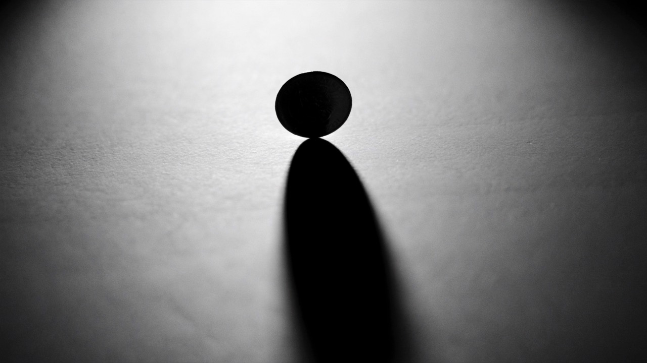 A single coin balanced on its edge, lit by dramatic light