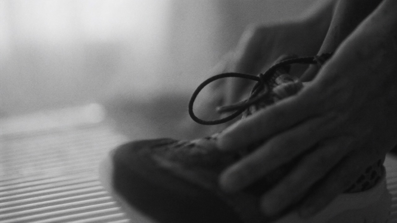 Black and white photo of hands lacing up running shoes before starting again